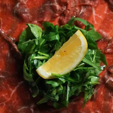 Thin-sliced beef carpaccio with arugula and lemon.