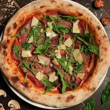 Bresaola pizza finished with arugula and parmigiano shavings.
