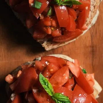 Tomato bruschetta on toasted bread, on a wooden board.