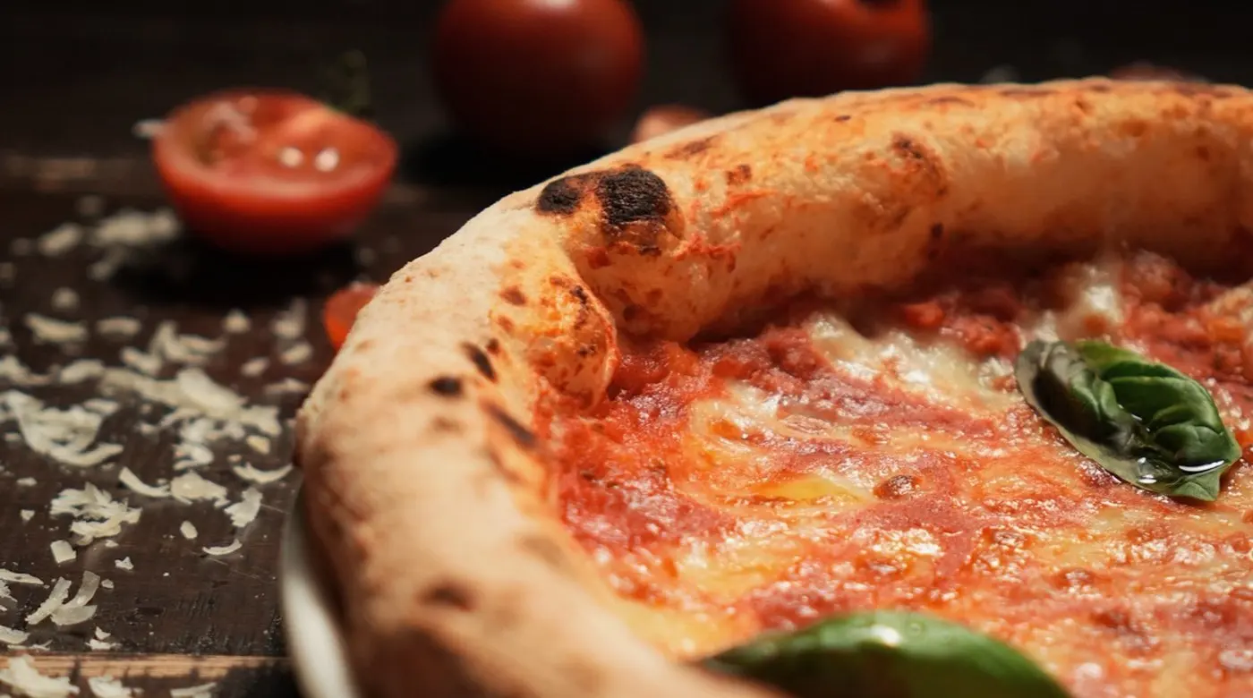 Close view of a Margherita's puffed, charred cornicione, blistered from the fire.